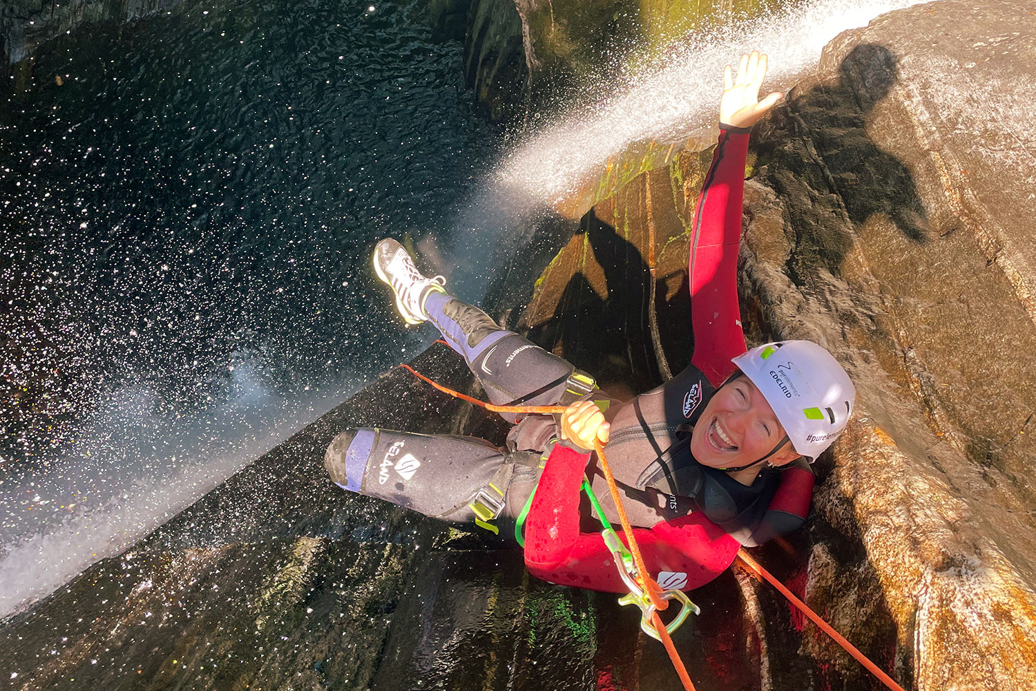 Lachend durchs Wasser: purelements® macht Canyoning im Tessin zu einem sicheren und unvergesslichen Erlebnis. 💦🧗♀️ Frau seilt sich lachend im Wasserfall des Val Grande ab – nachhaltiges Canyoning-Erlebnis mit purelements®