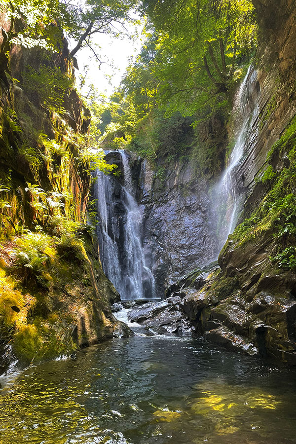 Wasserfall inmitten steiler Felsen und grüner Vegetation im Val Grande Canyon im Tessin